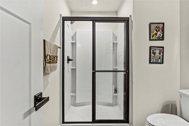 bathroom with a textured ceiling, a shower with door, and toilet