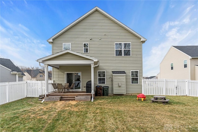 rear view of property featuring a yard, a deck, and an outdoor fire pit