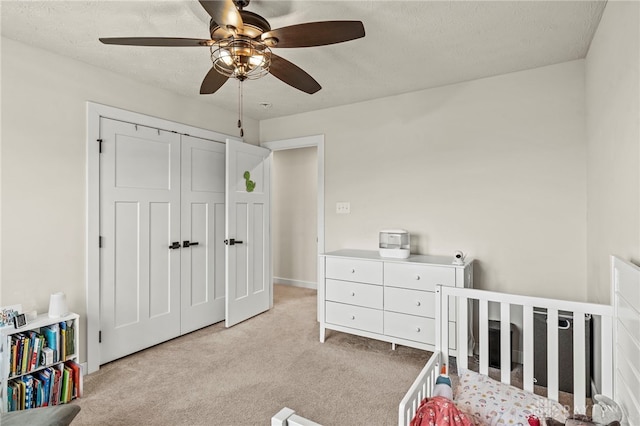 bedroom featuring ceiling fan, light colored carpet, a textured ceiling, and a closet