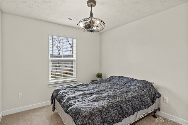 bedroom with light carpet, a notable chandelier, and a textured ceiling