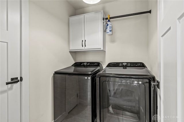 clothes washing area featuring cabinets and washer and clothes dryer