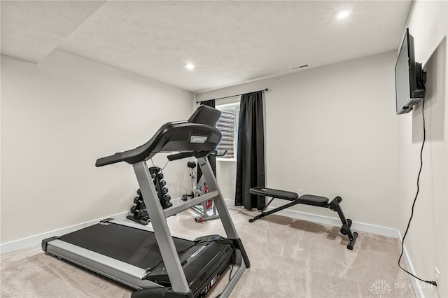 workout room featuring light colored carpet and a textured ceiling