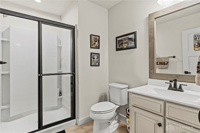 bathroom featuring a shower with door, vanity, tile patterned floors, and toilet