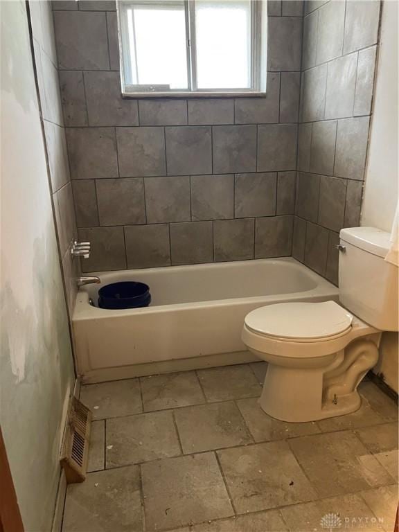 bathroom with tiled shower / bath combo and toilet