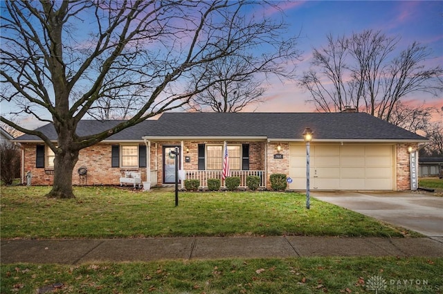 ranch-style home with a yard, a garage, and covered porch