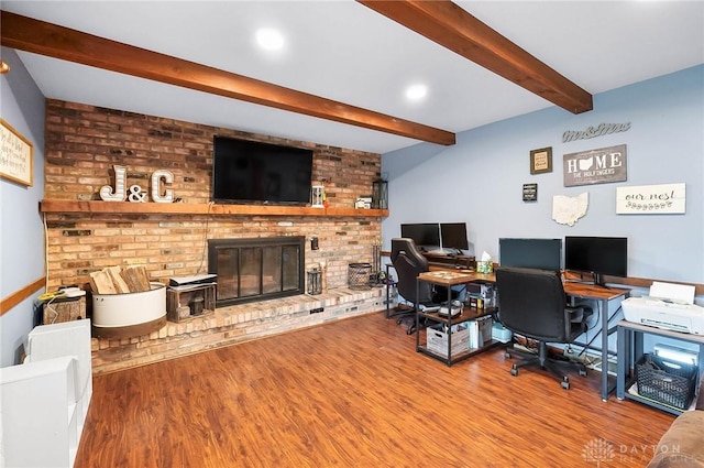 office area featuring wood-type flooring, a fireplace, and beam ceiling