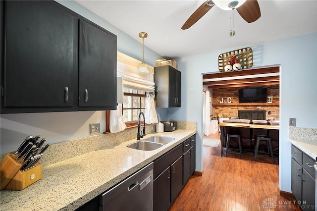 kitchen with pendant lighting, sink, light hardwood / wood-style flooring, dishwasher, and light stone counters