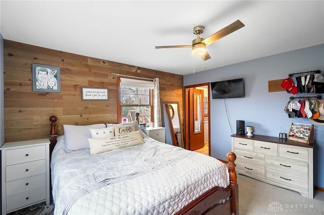 carpeted bedroom featuring ceiling fan and wood walls