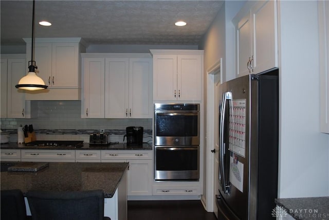 kitchen with stainless steel appliances, white cabinets, and decorative light fixtures