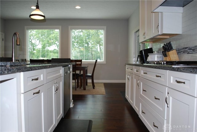 kitchen with white cabinetry, backsplash, decorative light fixtures, and wall chimney exhaust hood