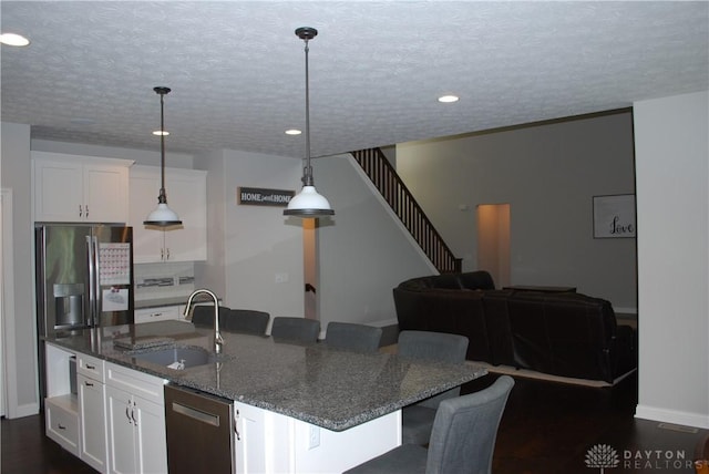 kitchen featuring sink, a breakfast bar area, white cabinetry, decorative light fixtures, and dark stone counters