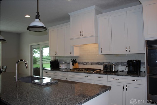 kitchen with stainless steel gas cooktop, sink, white cabinets, and dark stone counters