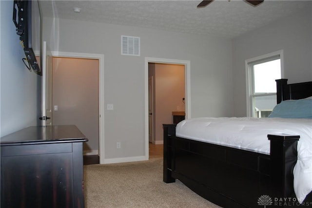 carpeted bedroom with connected bathroom, a textured ceiling, and ceiling fan