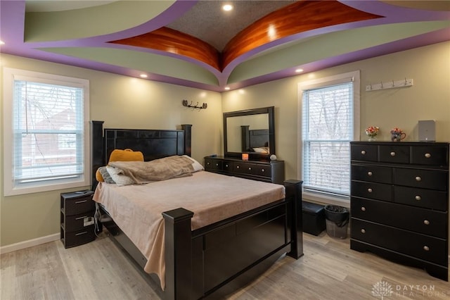 bedroom with lofted ceiling, multiple windows, and light wood-type flooring