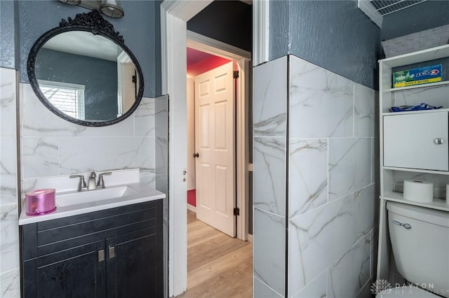 bathroom with vanity, hardwood / wood-style floors, tile walls, and toilet