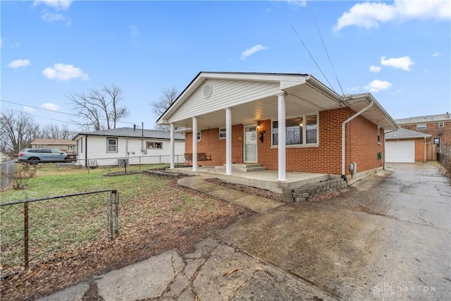 bungalow featuring a porch, a garage, an outbuilding, and a front lawn