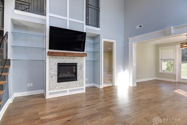 9460 Banyan Ct, Centerville, OH 45458 - unfurnished living room featuring built in shelves, a glass covered fireplace, wood finished floors, a high ceiling, and baseboards