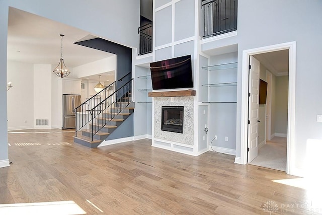 9460 Banyan Ct, Centerville, OH 45458 - unfurnished living room with visible vents, stairway, light wood-type flooring, a high ceiling, and a glass covered fireplace
