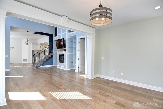 9460 Banyan Ct, Centerville, OH 45458 - spare room with baseboards, stairs, a glass covered fireplace, wood finished floors, and a notable chandelier