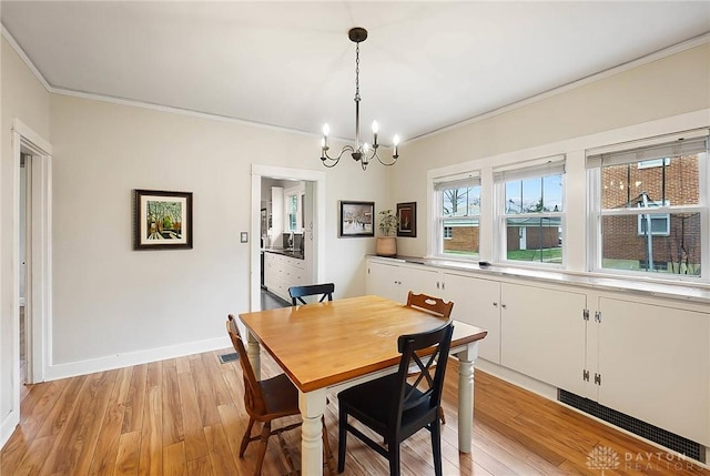 dining area featuring crown molding, an inviting chandelier, and light wood-type flooring