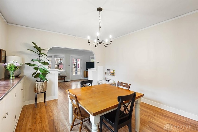 dining area featuring crown molding, a chandelier, and light wood-type flooring