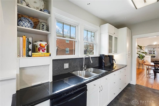 kitchen with tasteful backsplash, white cabinetry, black dishwasher, and sink