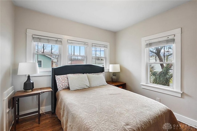 bedroom with multiple windows and dark hardwood / wood-style flooring