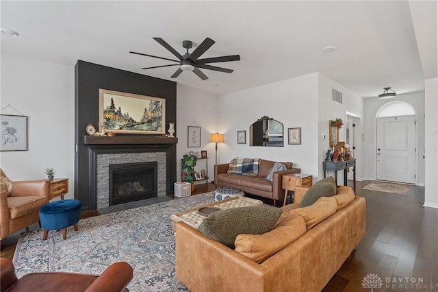 living room featuring ceiling fan, a fireplace, and dark hardwood / wood-style floors