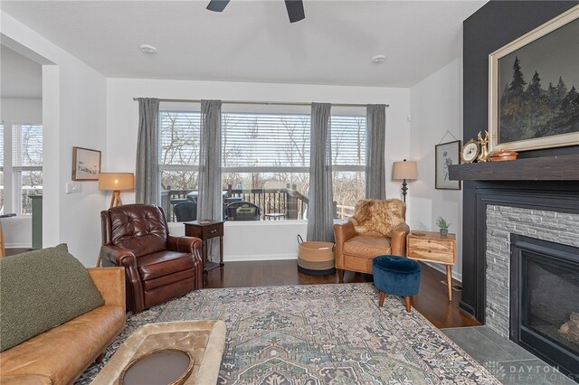 living room featuring plenty of natural light, a stone fireplace, and dark hardwood / wood-style flooring