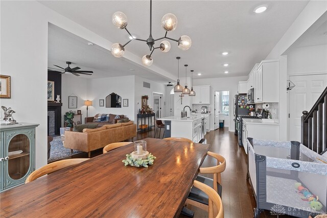 dining space featuring dark wood-type flooring, ceiling fan, and sink