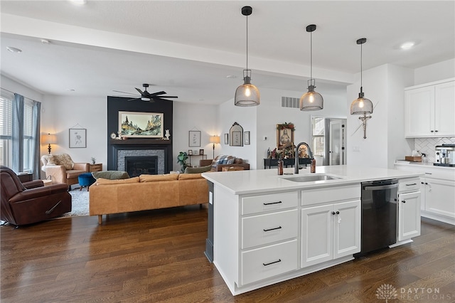 kitchen featuring sink, a kitchen island with sink, hanging light fixtures, white cabinetry, and black dishwasher