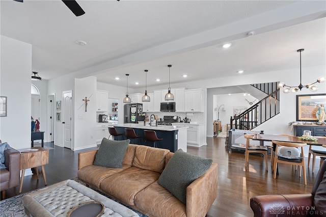 living room with ceiling fan with notable chandelier, dark hardwood / wood-style floors, and sink