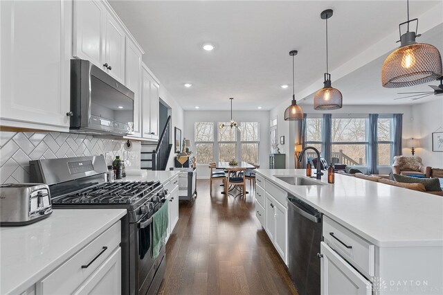 kitchen featuring sink, a center island with sink, pendant lighting, stainless steel appliances, and white cabinets