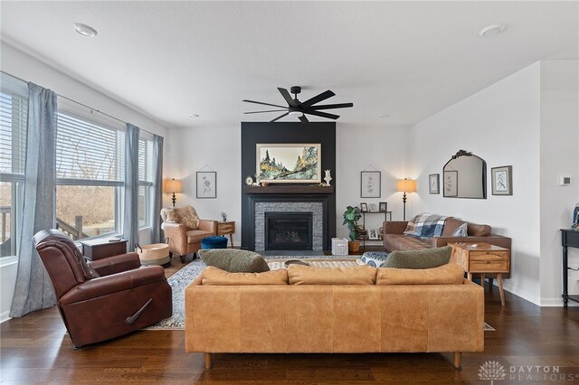 living room featuring dark wood-type flooring, a fireplace, and ceiling fan