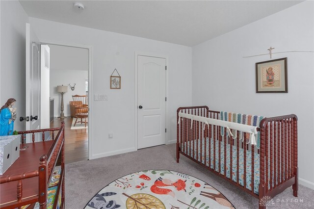 bedroom featuring a nursery area and light colored carpet