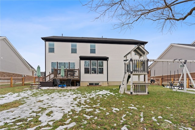 rear view of house with a playground, a wooden deck, and a lawn