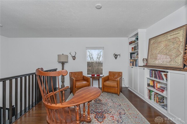 sitting room with dark wood-type flooring and a textured ceiling