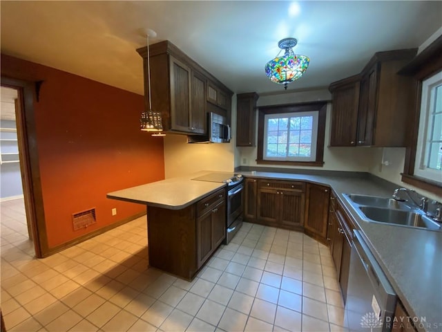 kitchen featuring dark brown cabinetry, sink, hanging light fixtures, appliances with stainless steel finishes, and kitchen peninsula