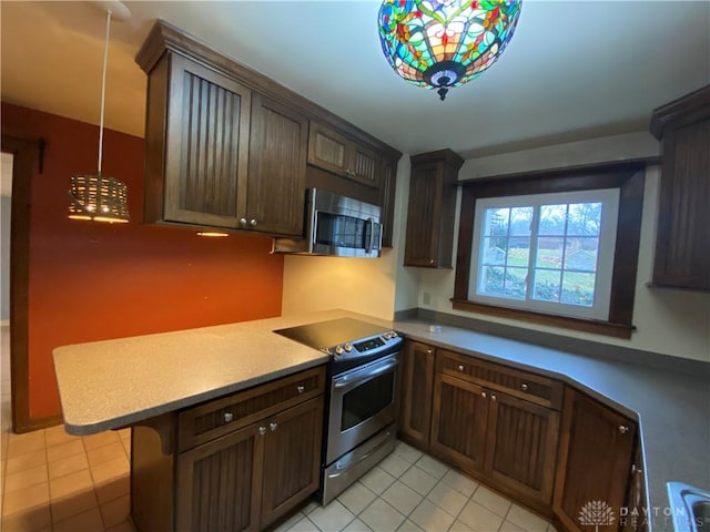 kitchen with a breakfast bar, hanging light fixtures, light tile patterned floors, kitchen peninsula, and stainless steel appliances