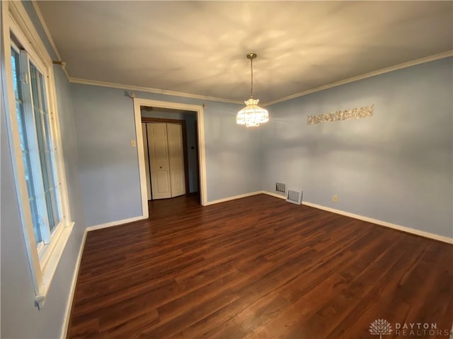 empty room featuring dark wood-type flooring, crown molding, and a chandelier