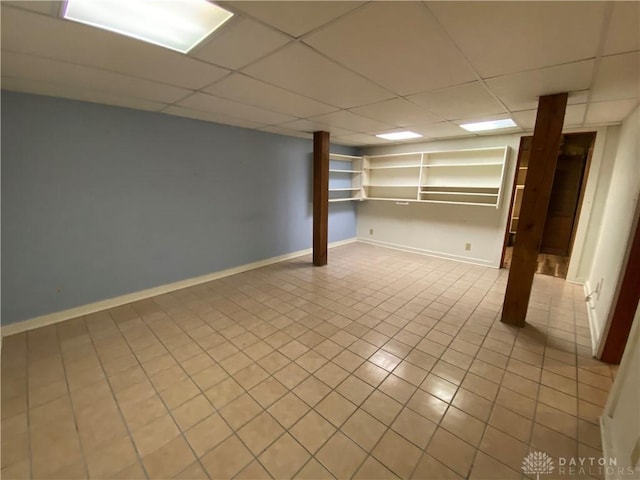 basement featuring light tile patterned flooring and a paneled ceiling