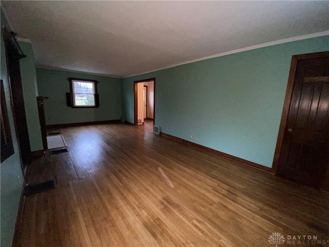 unfurnished living room featuring hardwood / wood-style flooring and crown molding