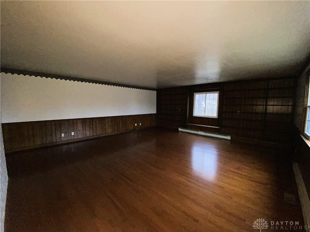 unfurnished room featuring dark wood-type flooring and baseboard heating