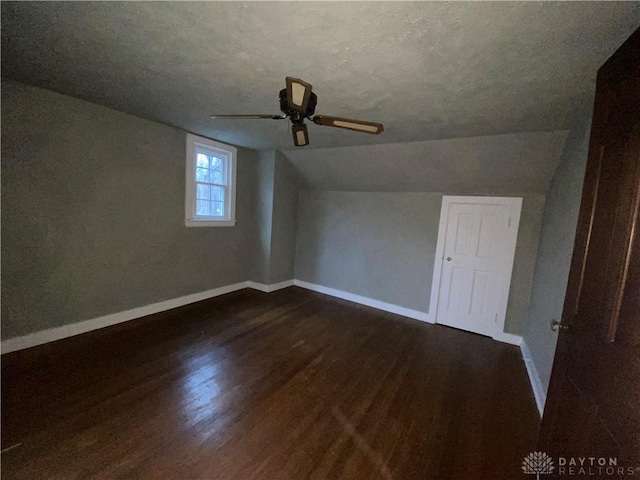 additional living space featuring lofted ceiling, a textured ceiling, dark wood-type flooring, and ceiling fan