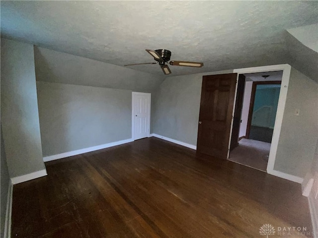 bonus room featuring dark wood-type flooring, ceiling fan, vaulted ceiling, and a textured ceiling