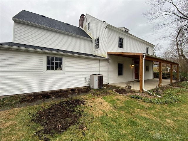 back of property with central AC unit, a patio area, and a lawn