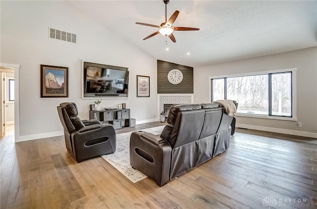 living room with wood-type flooring, high vaulted ceiling, ceiling fan, and a fireplace