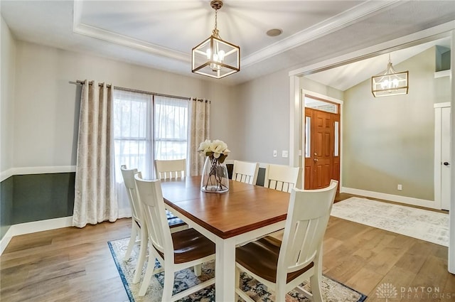 dining room with vaulted ceiling, ornamental molding, hardwood / wood-style floors, and an inviting chandelier