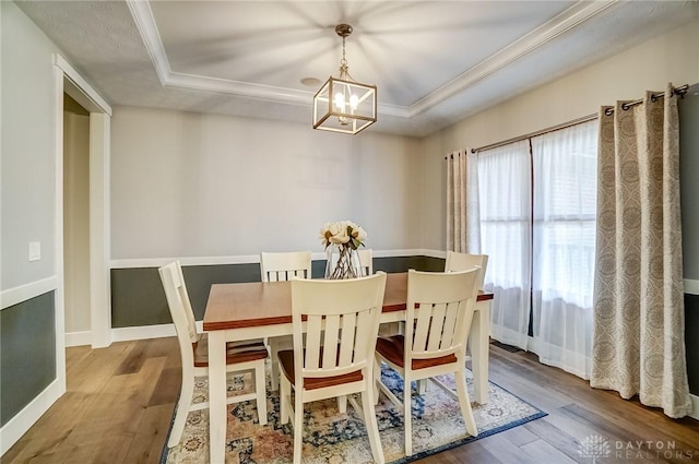 dining room with hardwood / wood-style flooring, ornamental molding, and a tray ceiling