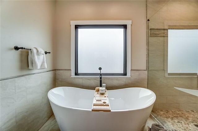 bathroom with tile walls and a tub to relax in